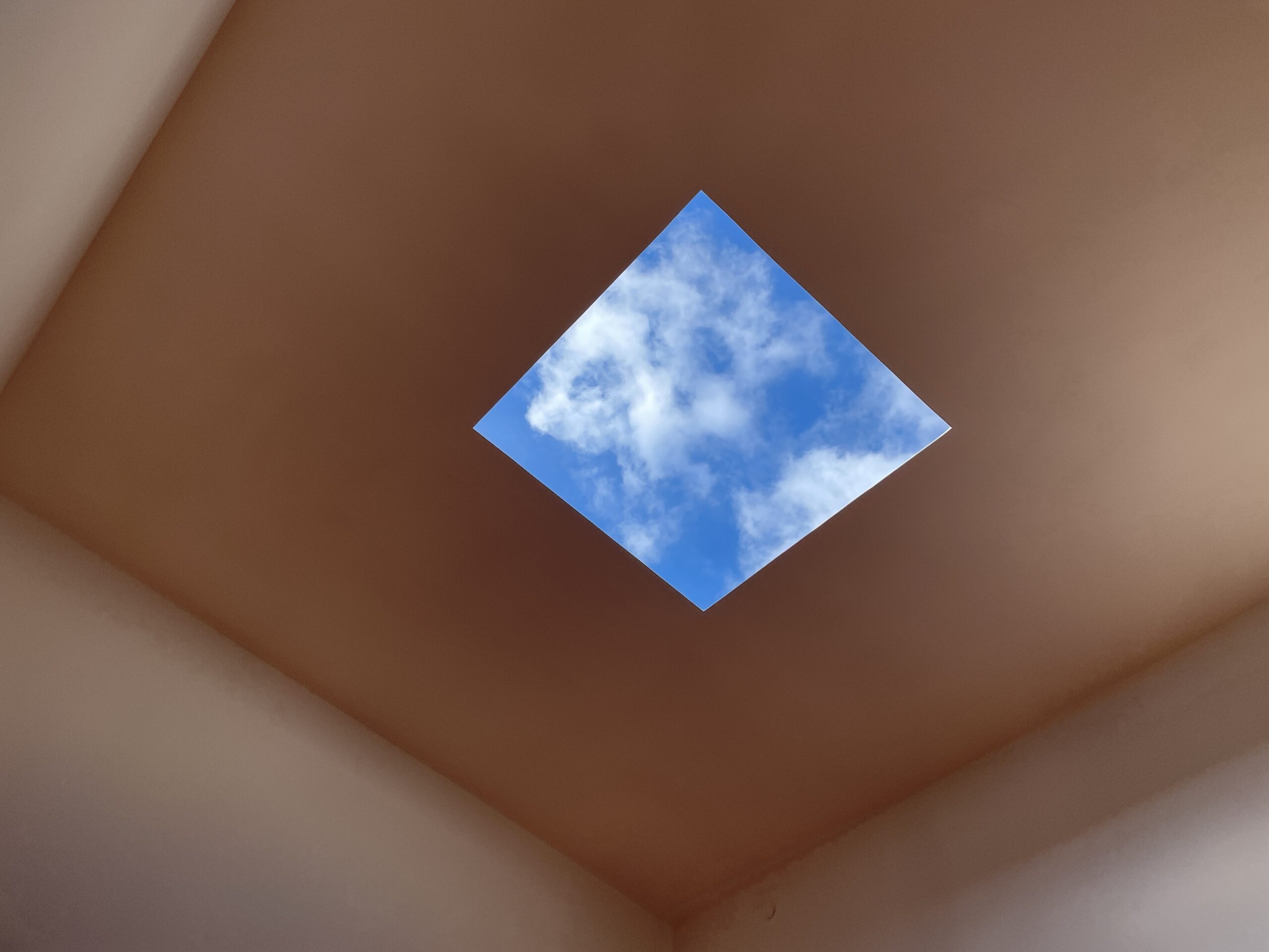 James Turrell's Skyspace at Friends Seminary School in New York, with the aperture open to the blue sky and clouds 